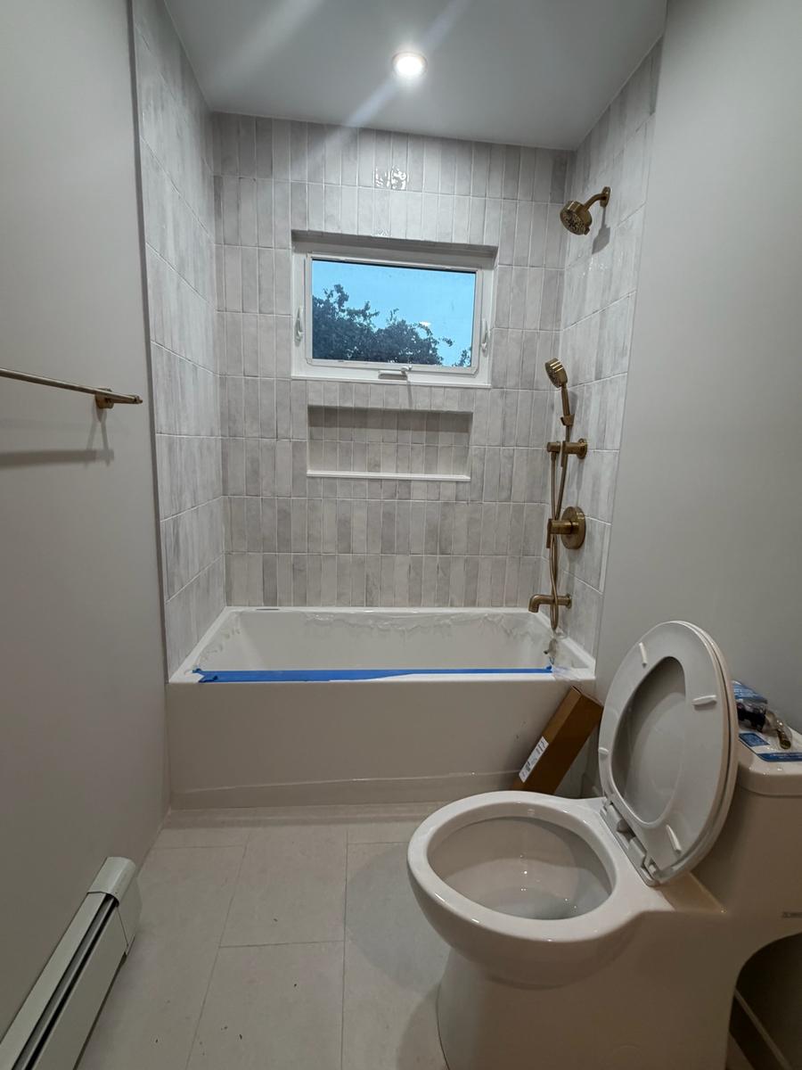 Completed bathroom with tile surround and brass shower fixtures