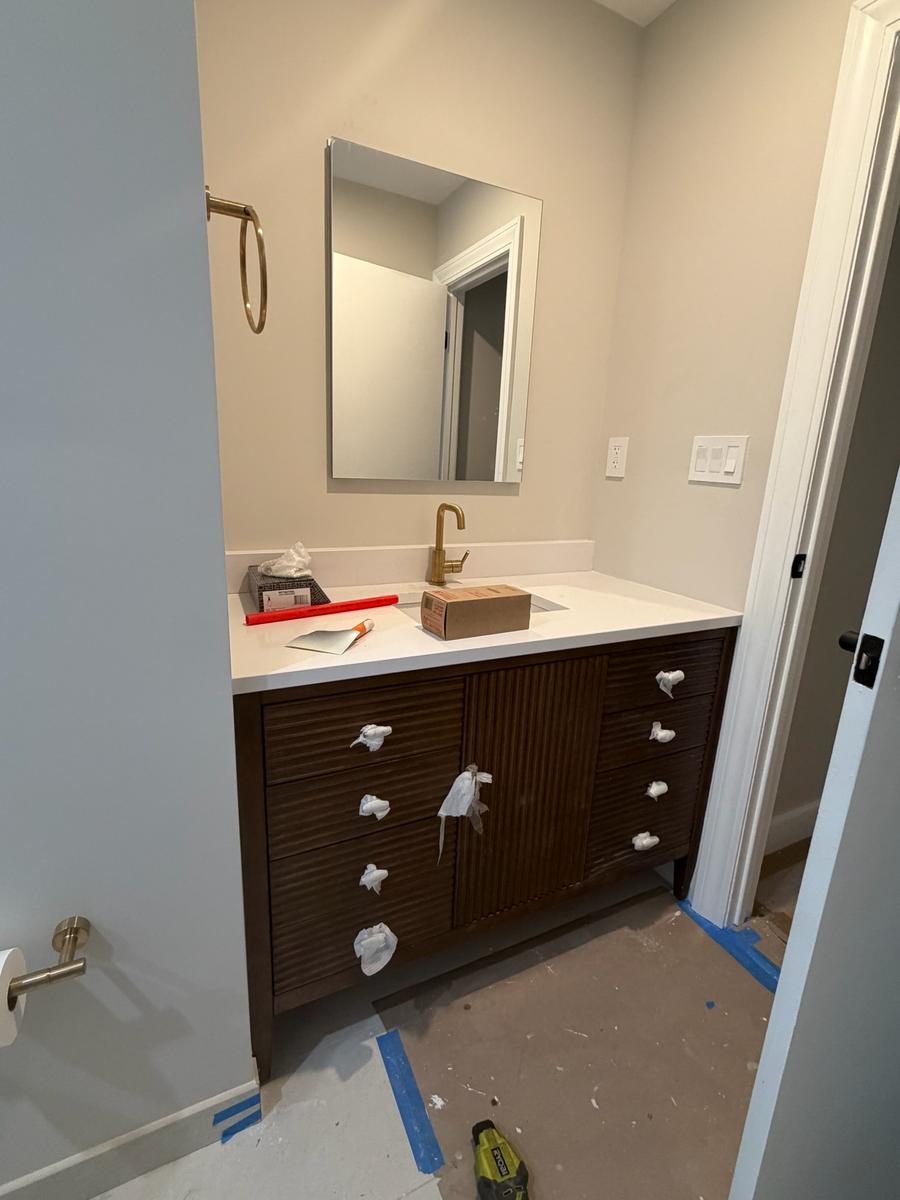 Dark wood vanity with quartz countertop and brass faucet