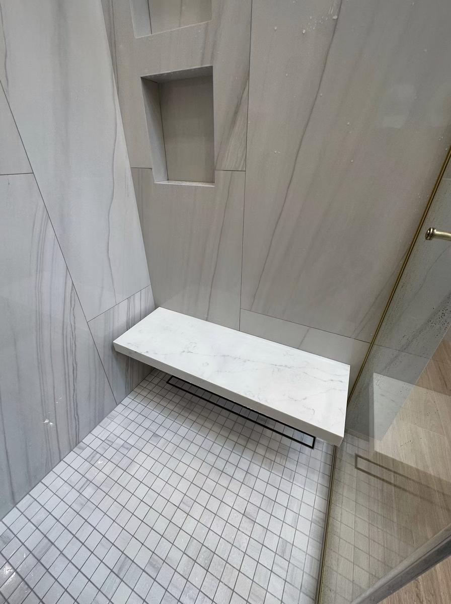 Built-in marble shower bench with mosaic tile accent in custom bathroom renovation