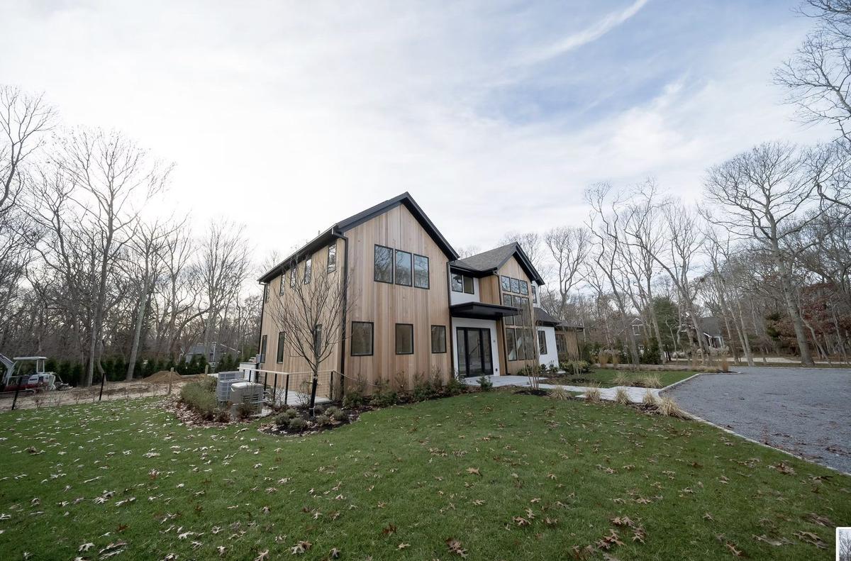 Side exterior view of East Hampton modern farmhouse showing covered porch and landscaping