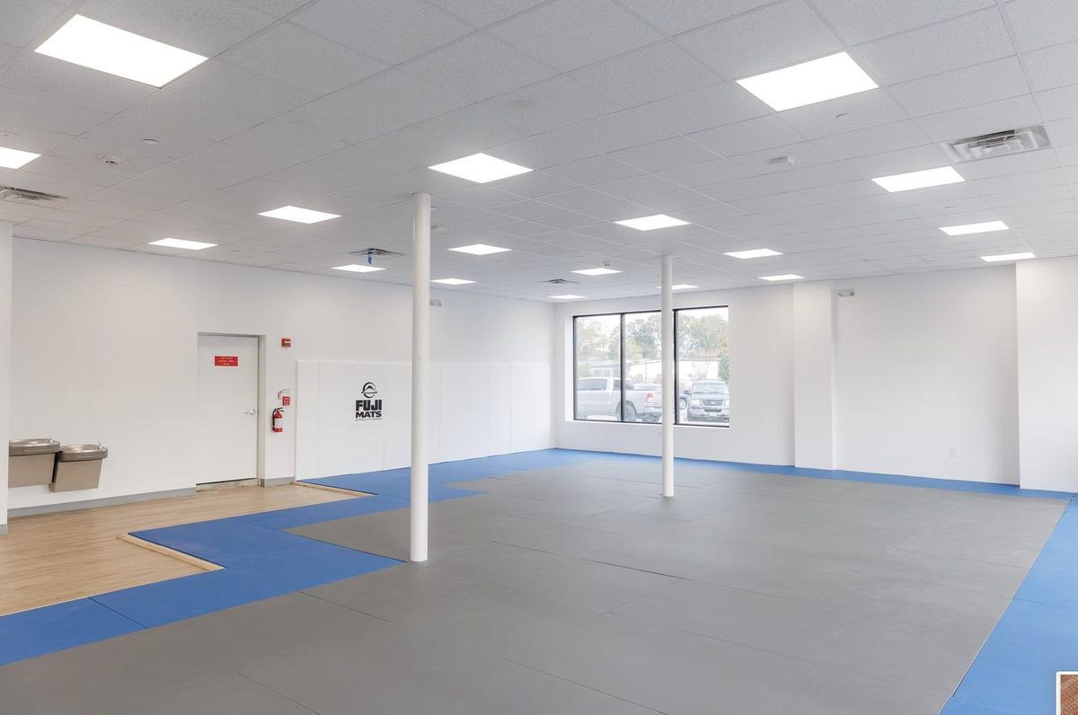 Training floor with padded mats and custom lighting in commercial gym buildout