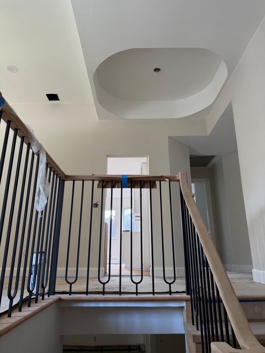 Stairwell after renovation: oak treads, custom iron balusters and a white coffered ceiling dome