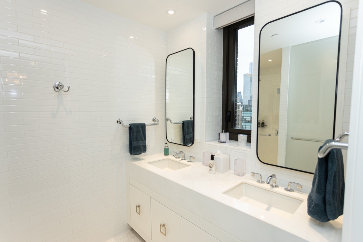 Bathroom with a floating double vanity, black-framed mirrors and white tile