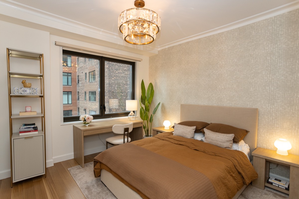 Bedroom with a built-in desk under the window, textured wallcovering and a crystal pendant