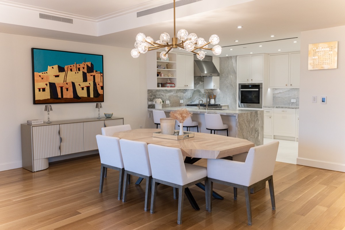 Dining room with a sculptural brass chandelier and seating for eight, open to the kitchen