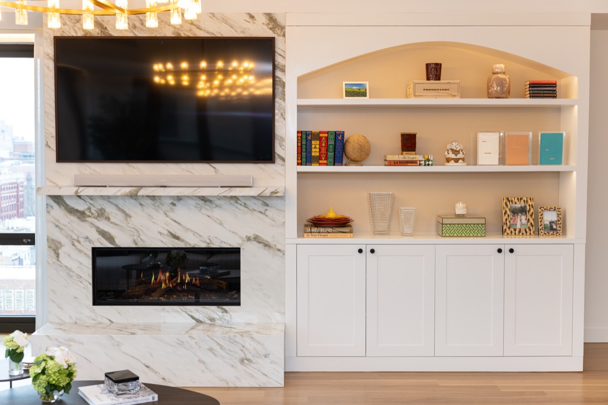 Detail of the linear fireplace, marble surround and custom arched shelving with integrated lighting