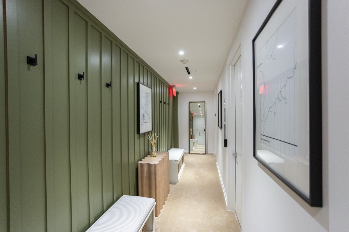 Hallway with green board-and-batten paneling, black hooks and a built-in bench