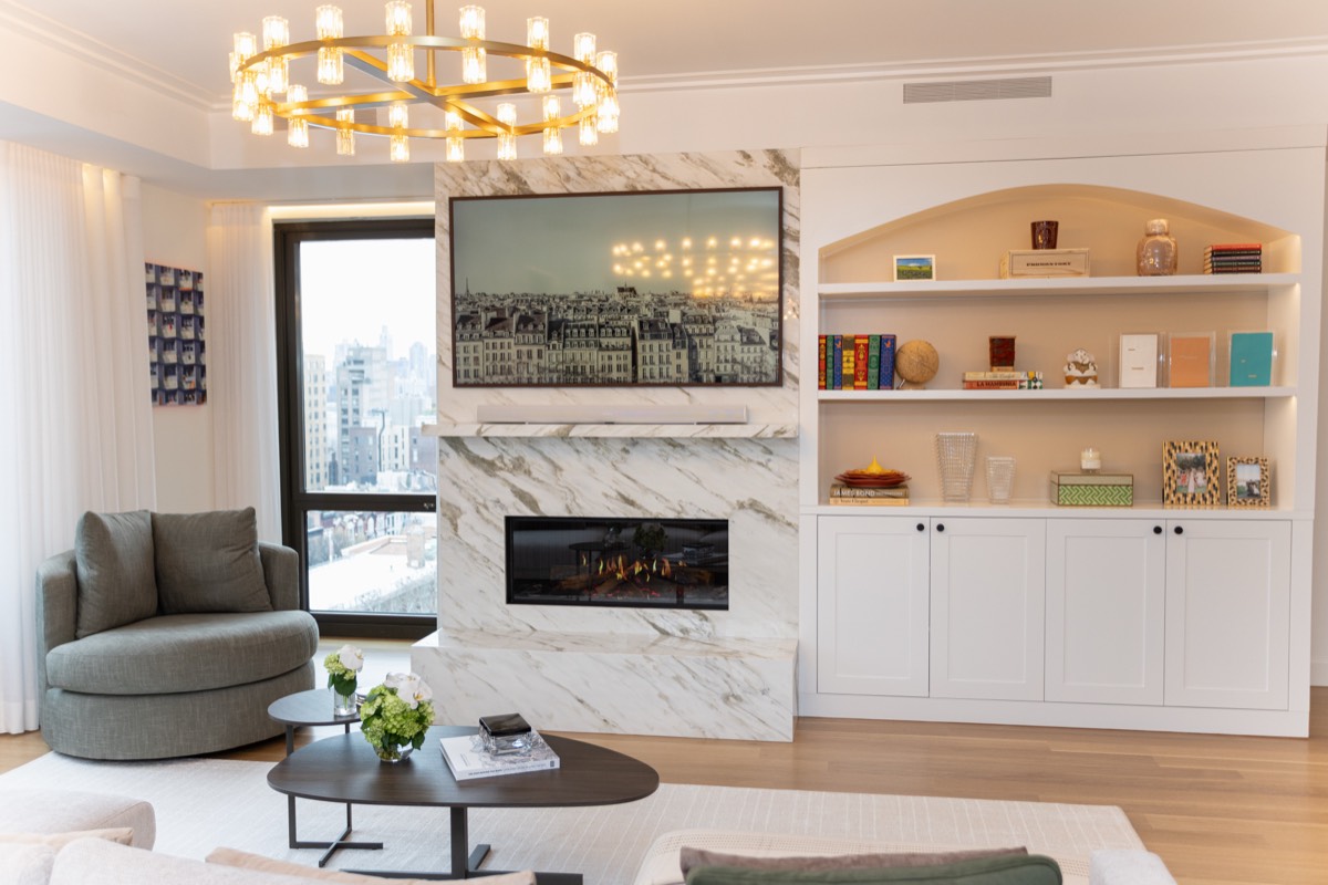 Floor-to-ceiling marble fireplace surround beside an arched, lit built-in with shaker cabinets below